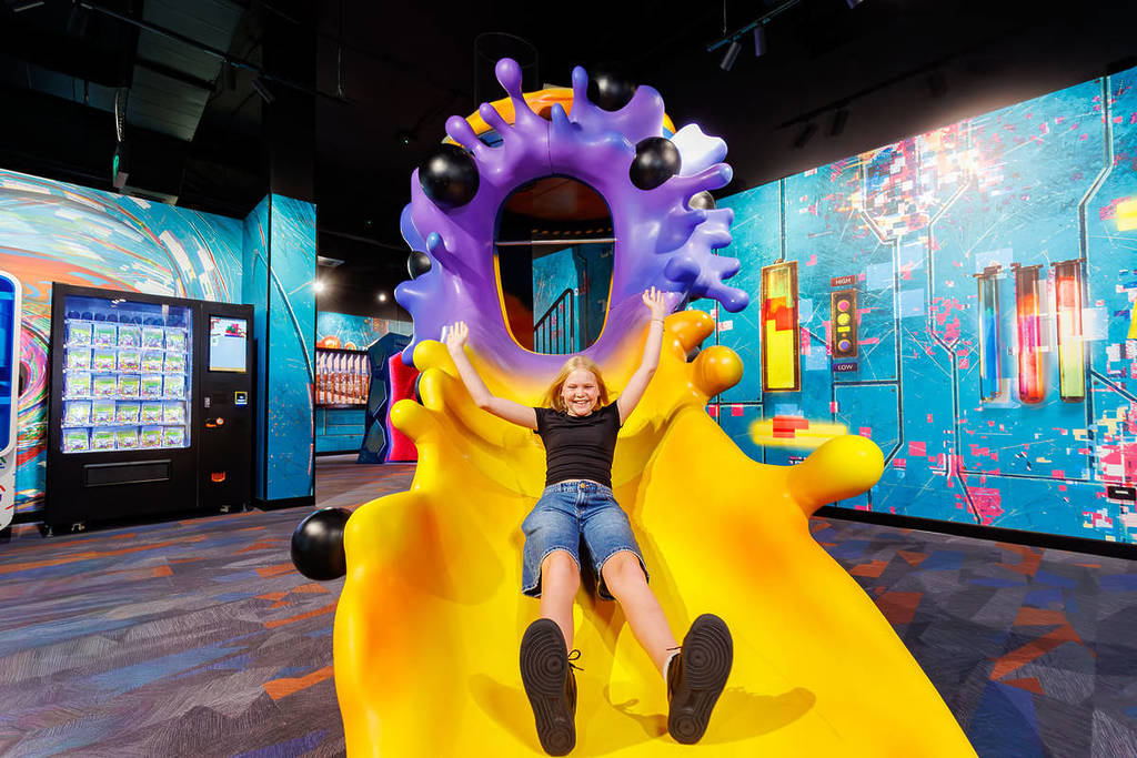 A young girl on a purple and yellow slide at TRICKD: Illusions, Fun & More.