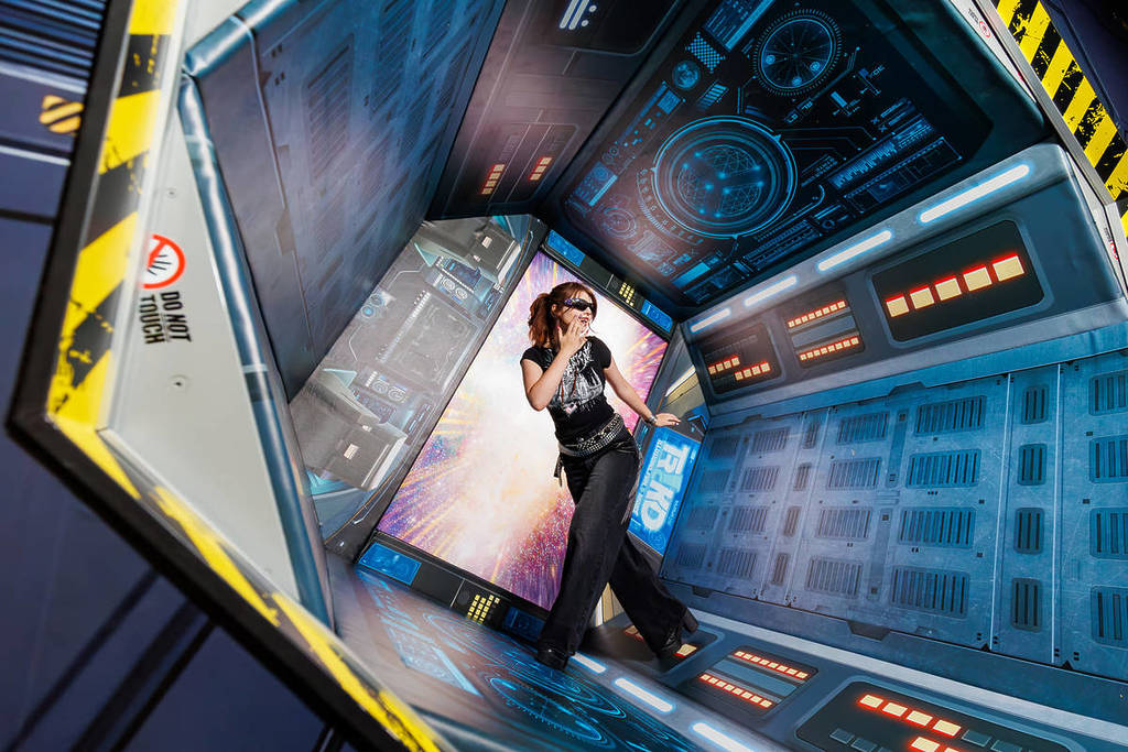 A young woman poses in a round spaceship room at TRICKD: Illusions, Fun & More.