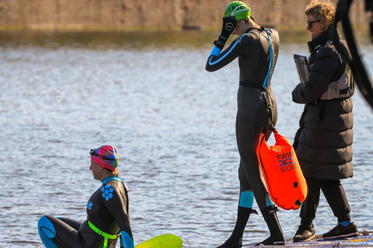 Two people in wet suits prepared to outdoor swimming in Bristol Floating Harbour