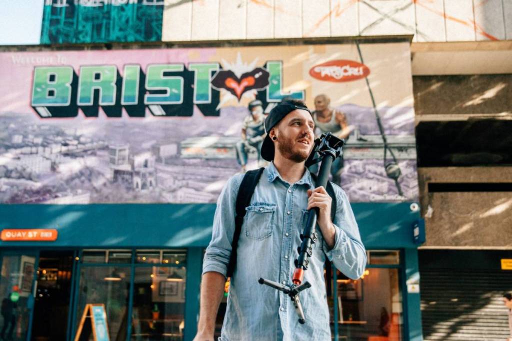 man holding camera tripod standing near store