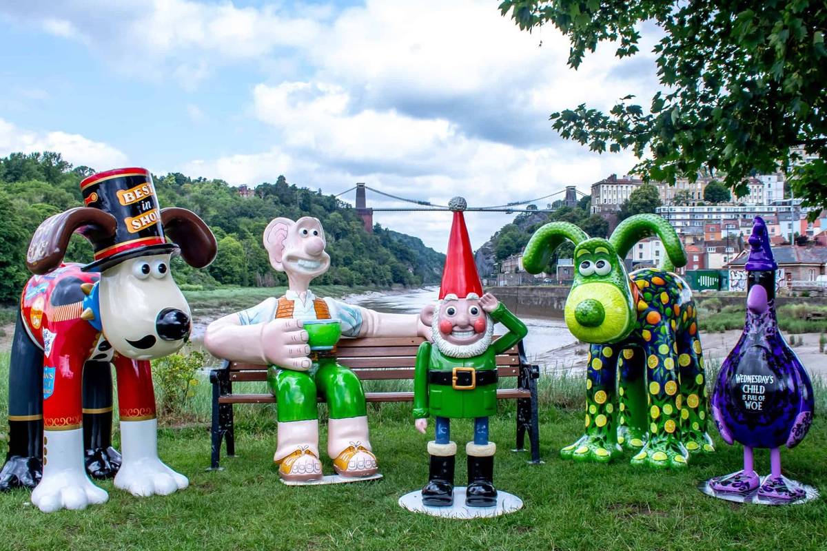 A line-up of Gromit Unleashed 3 sculptures in front of Clifton Suspension Bridge In Bristol