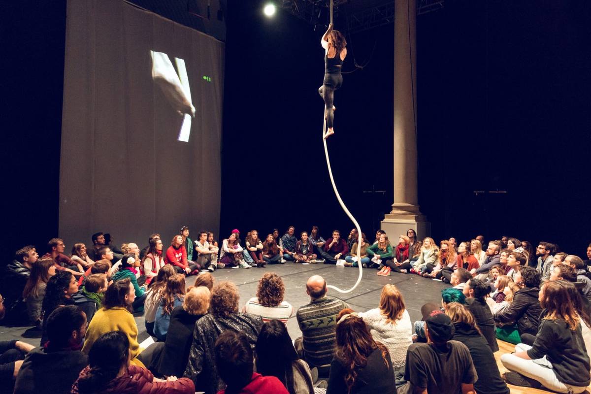 A ring of people surrounding a circus performer on a rope in Bristol