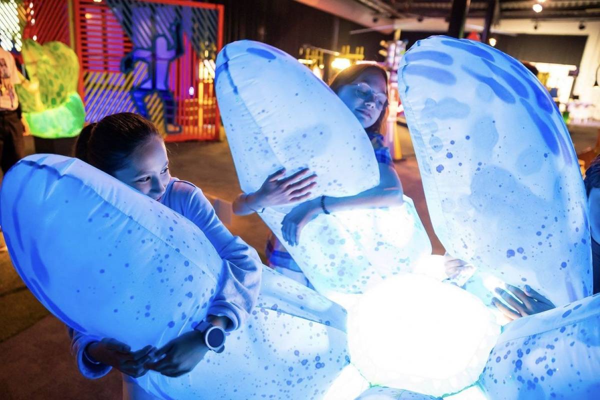 young children cuddling giant robotic inflatables lit up.