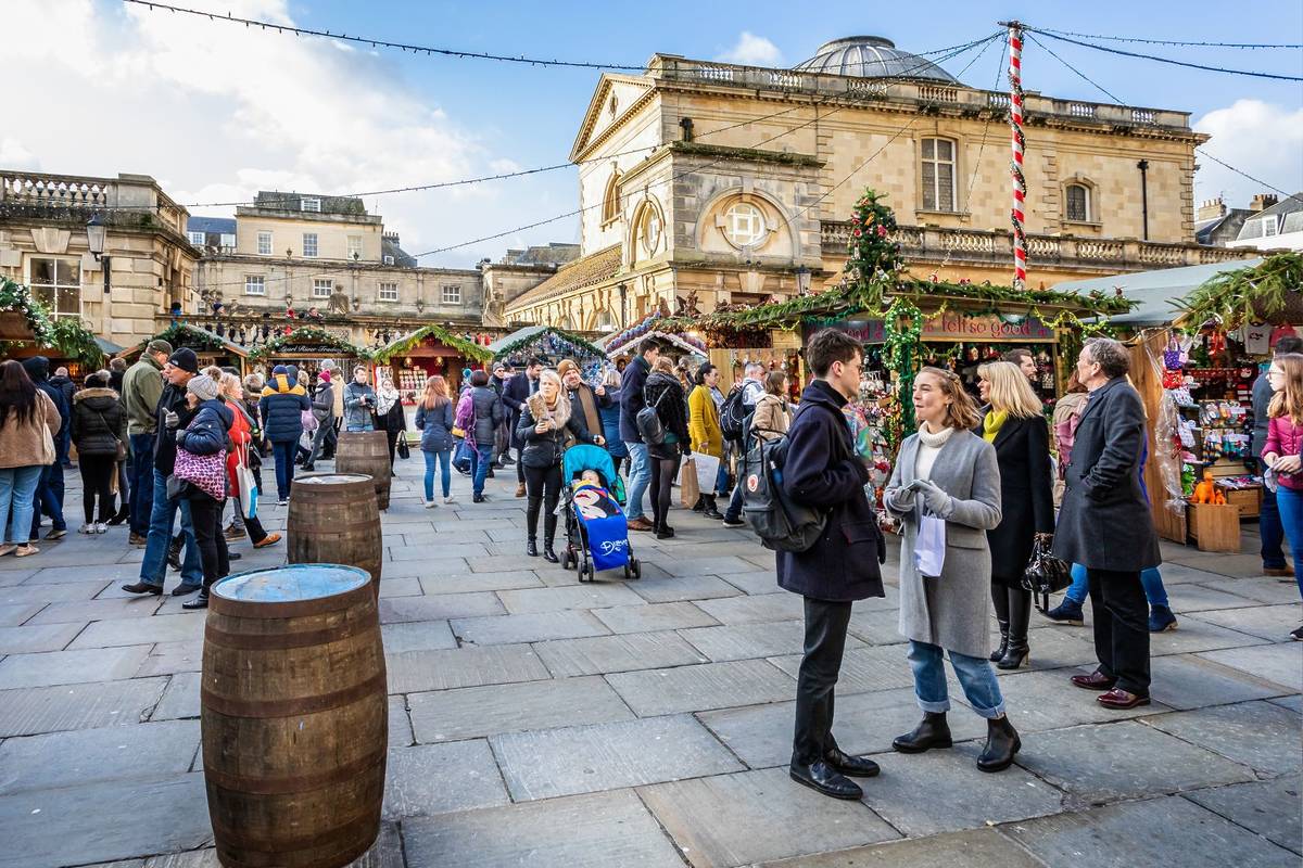 Market stalls and Roman Baths near the Bath Abbey at Bath Christmas Market, Bath, Somerset, UK on 13 December 2019