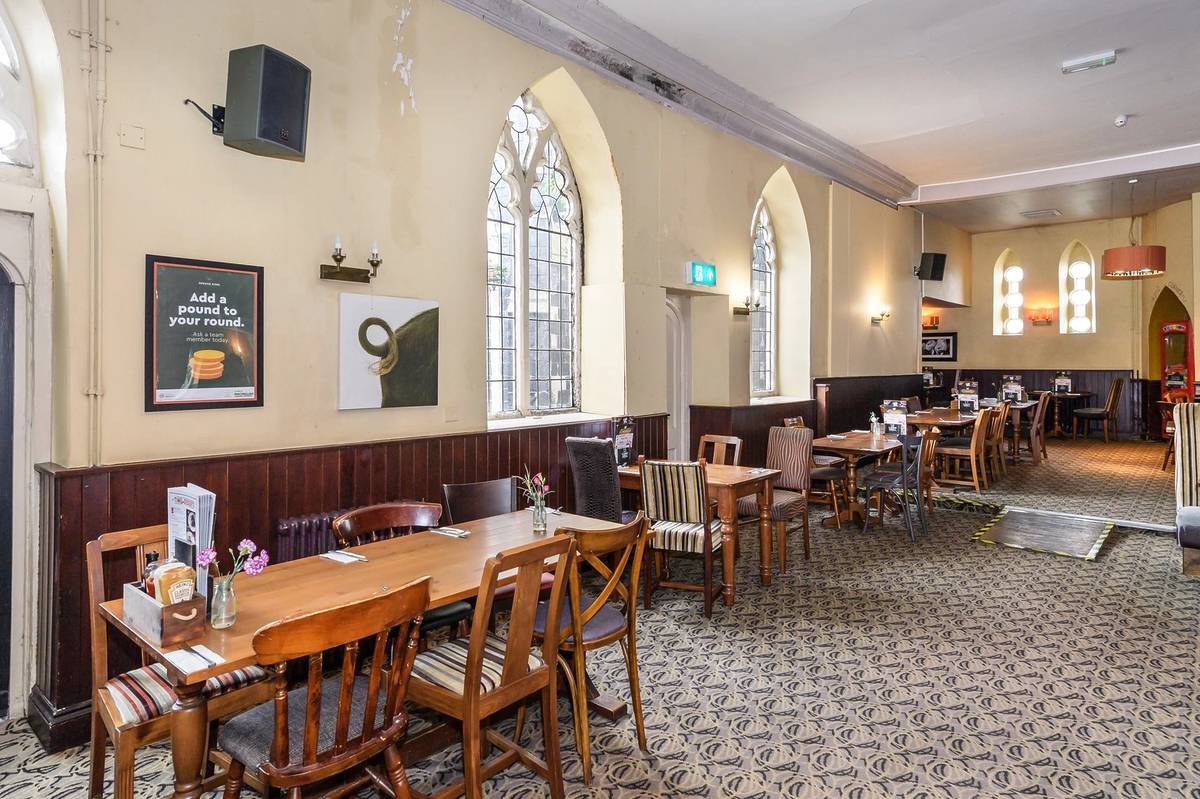 Inside of the Black Castle with wooden chairs, patterned carpet and arched Gothic windows