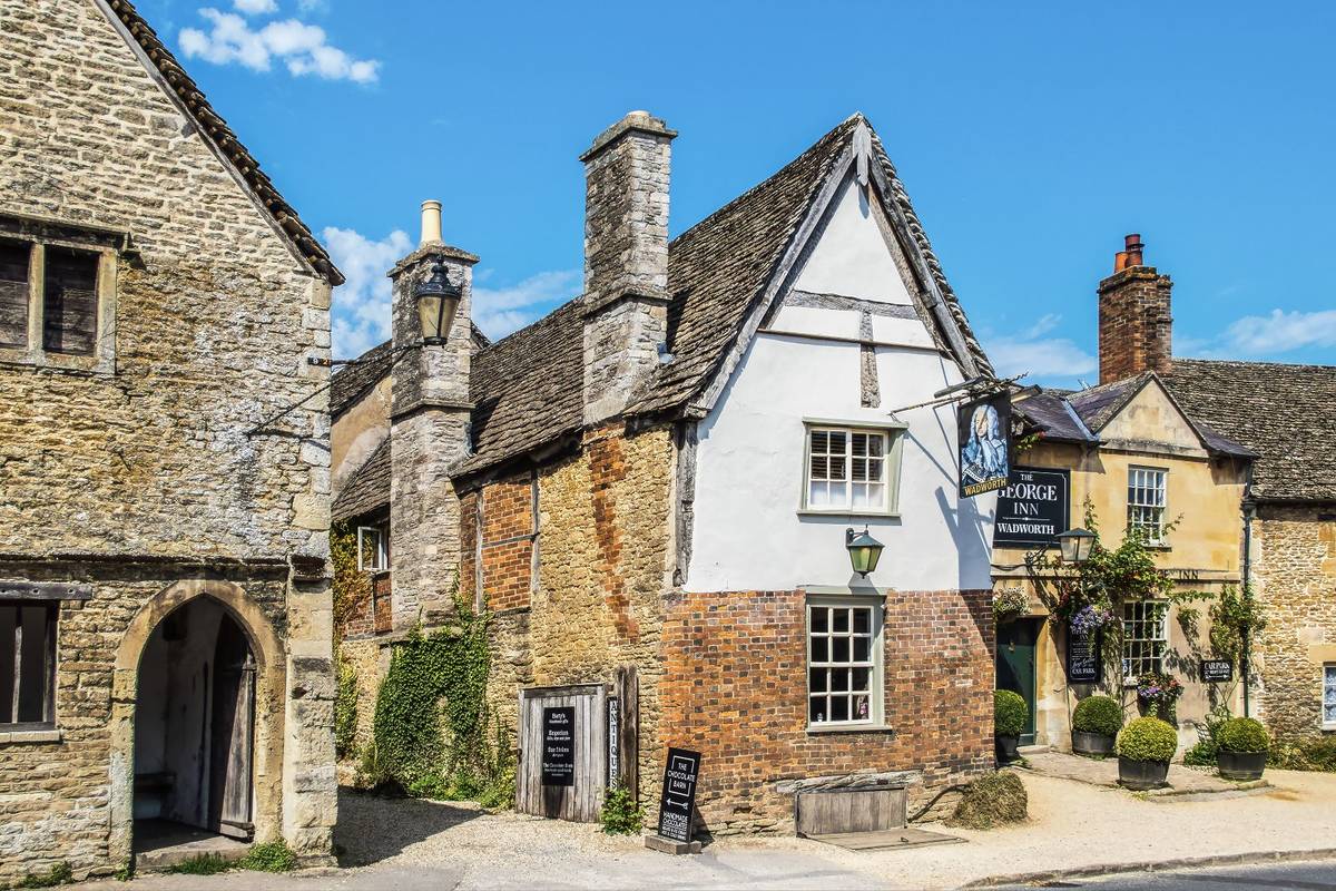 July 25 2019 Lacock UK - Street scene and alley in Cotswold village of Lacock where scenes from Downton Abbey were shot - the George Inn- Wadworth