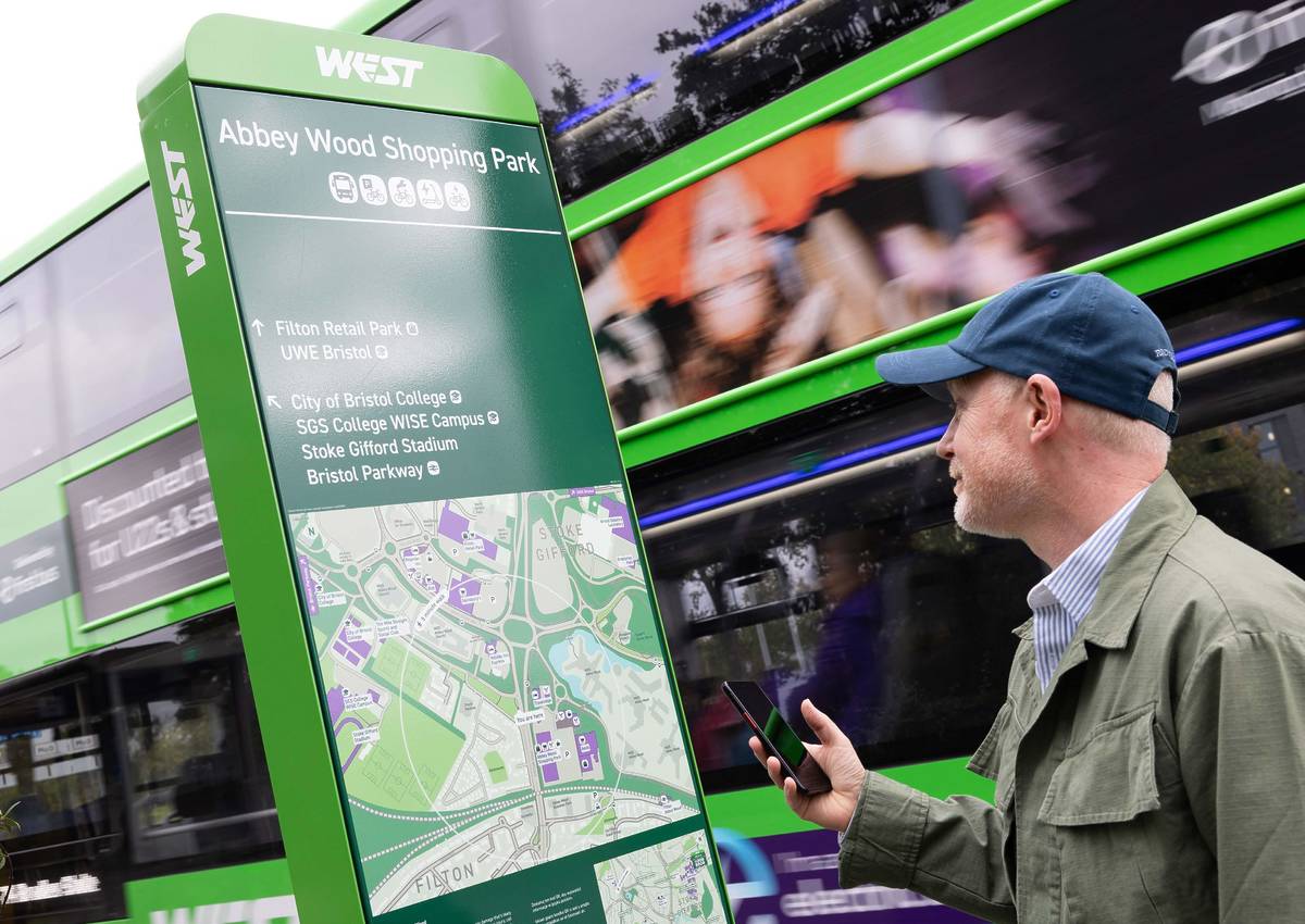 man looking at map with green bus going past