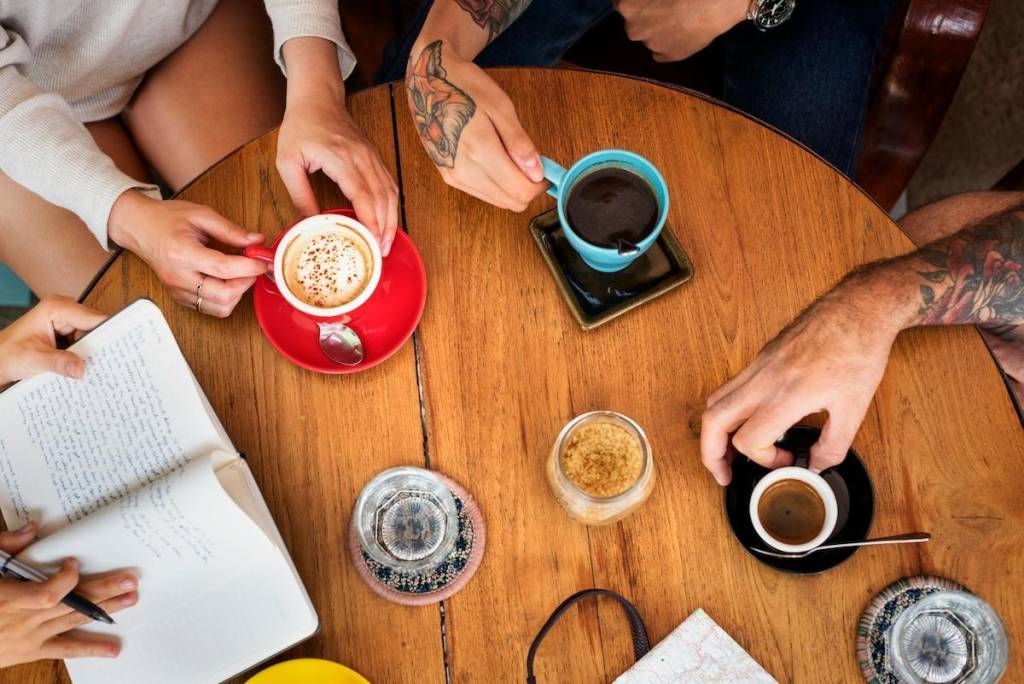 a birds eye view of a coffee table with people around it drinking coffee and studying