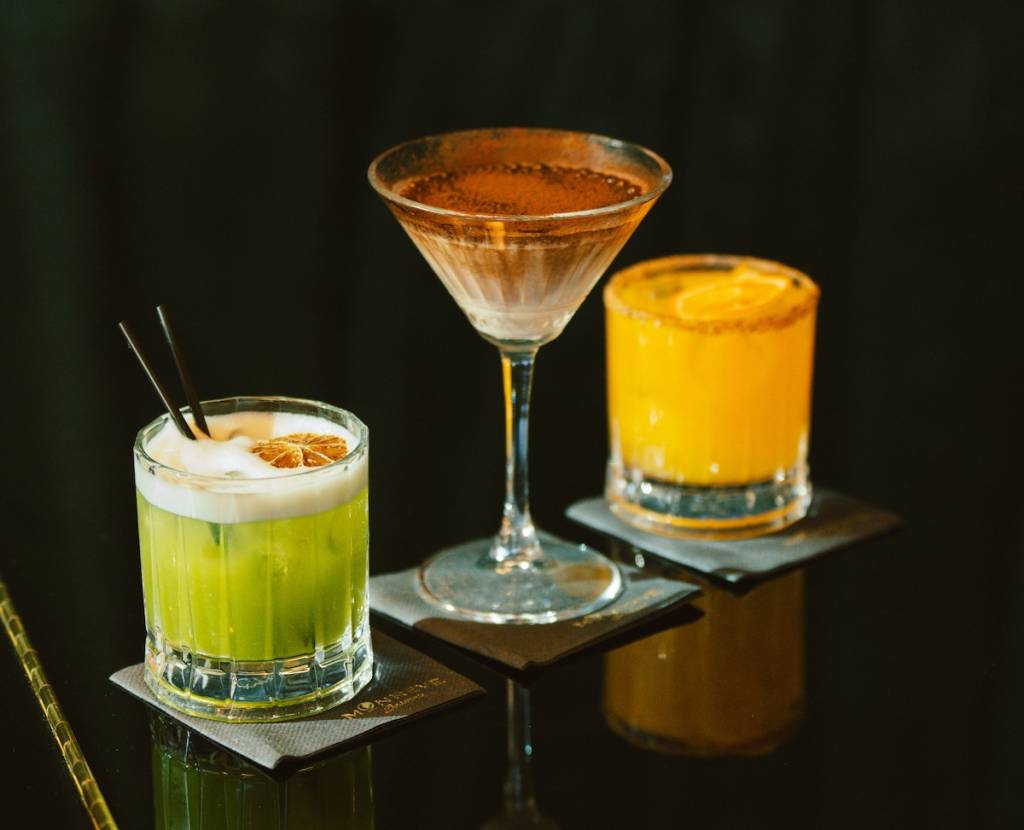 three cocktails on a black bar top