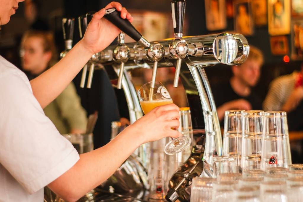 person pulling pints at a taproom