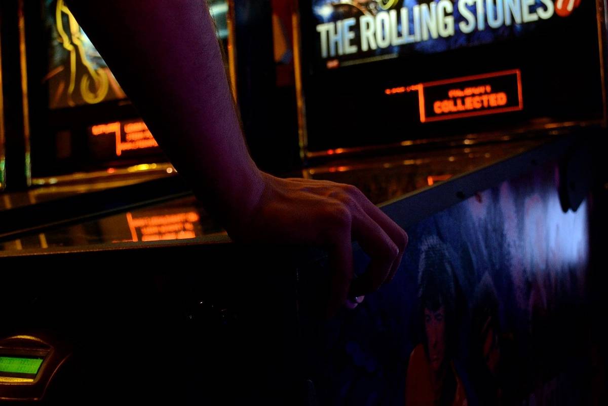 Hand leaning on pinball machine at the Green Room Arcade
