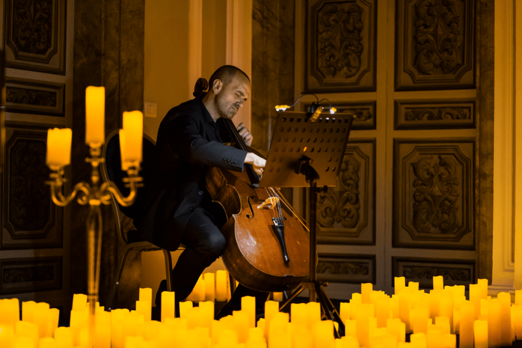 A musician playing the cello surrounded by a sea of candles