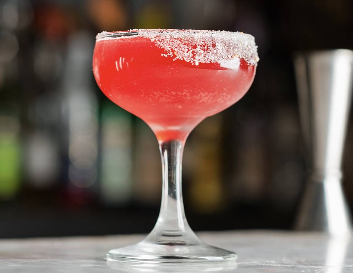 red cocktail in a clear glass with sugar on the rim from Violet Hour