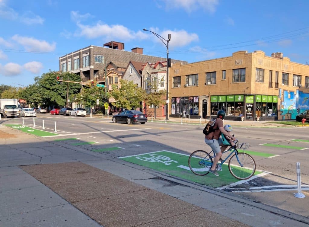 Un padre montando en bici con su hijo por una calle de la ciudad
