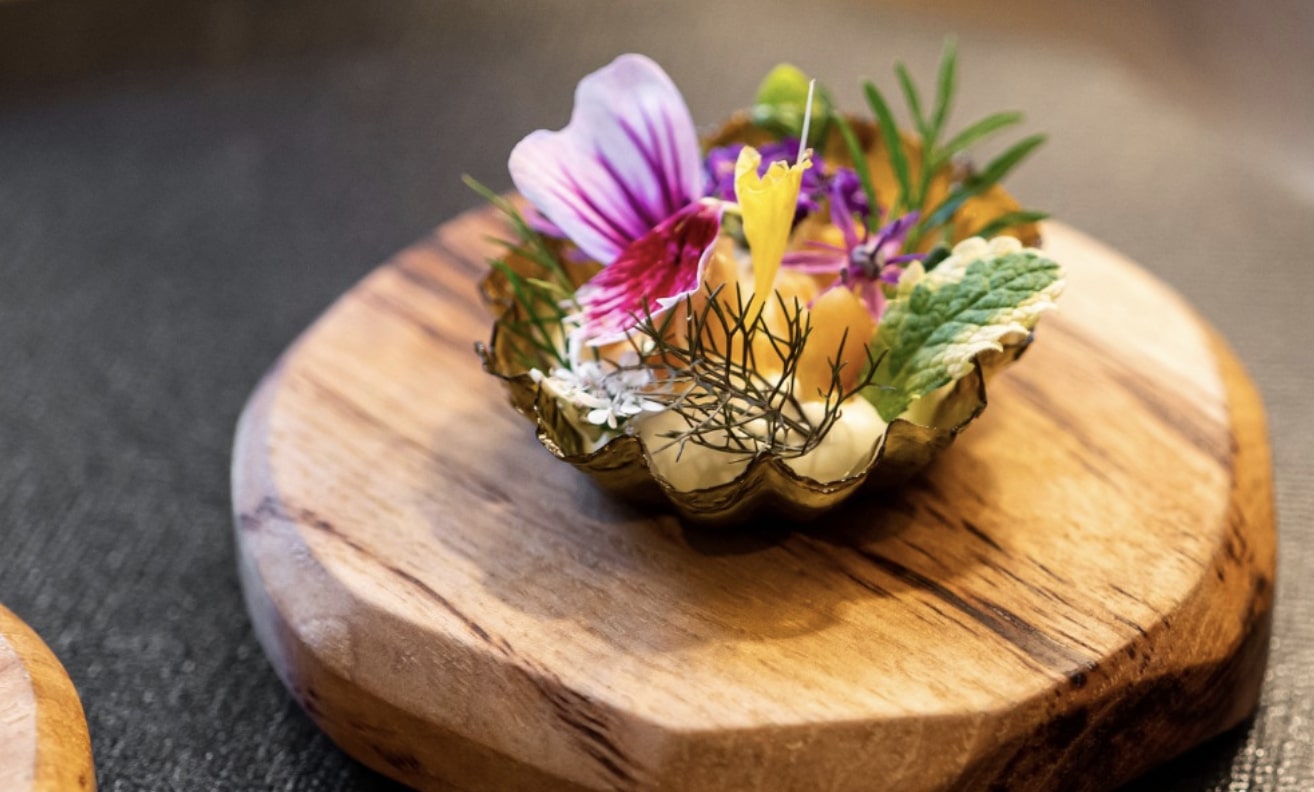 a celebrated dish with flowers and garnishes on a wooden platter from Smyth in Chciago
