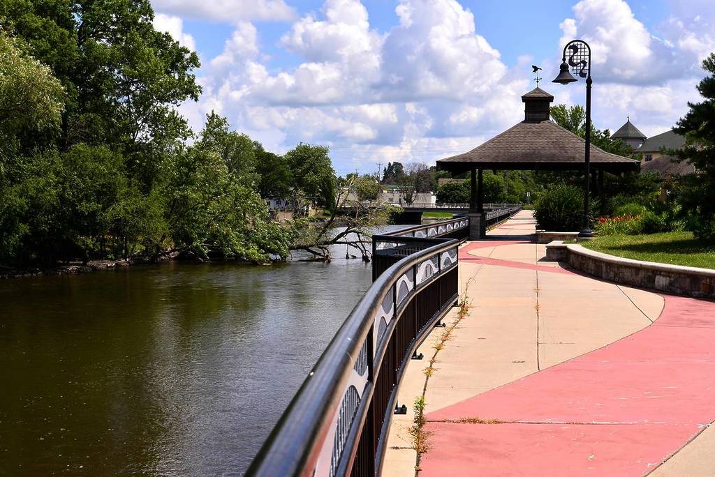 The walk way along the Fox River in Burlington Wisconsin on a beautiful mid summer afternoon with clouded blue skies and a pavilion along the walk.