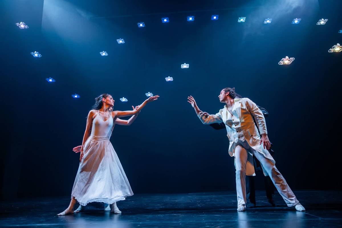man and women reach across to touch each other across the stage