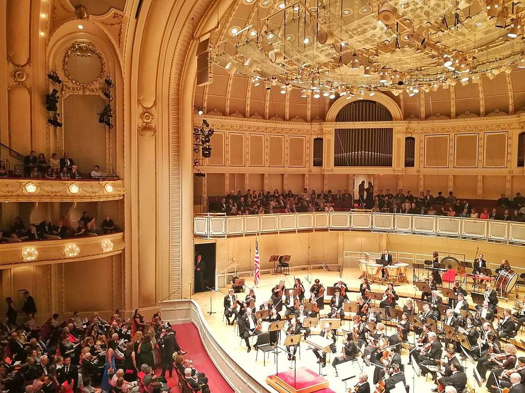 An orchestra performs in a large hall.