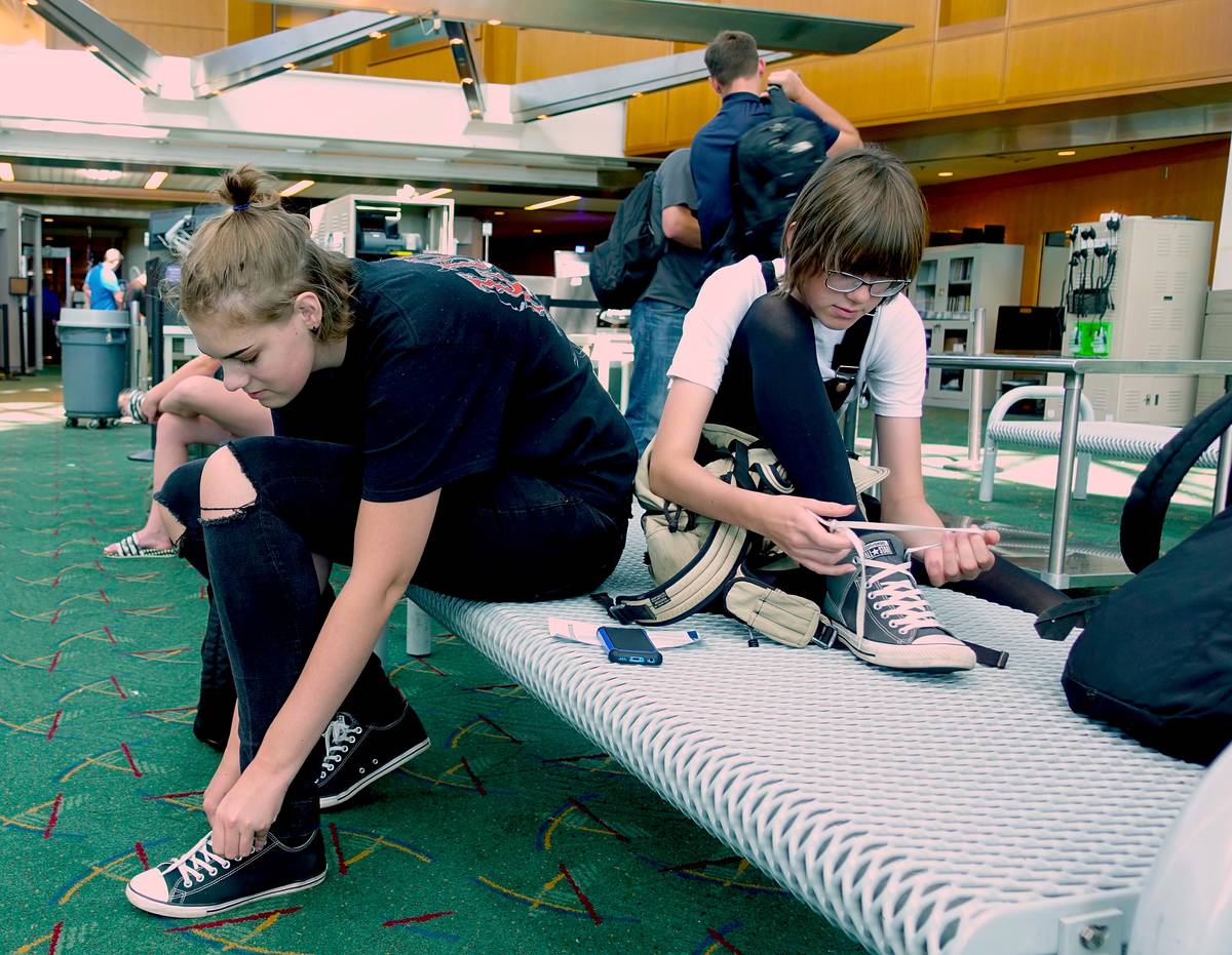 Travelers put their shoes back on after passing through airport security