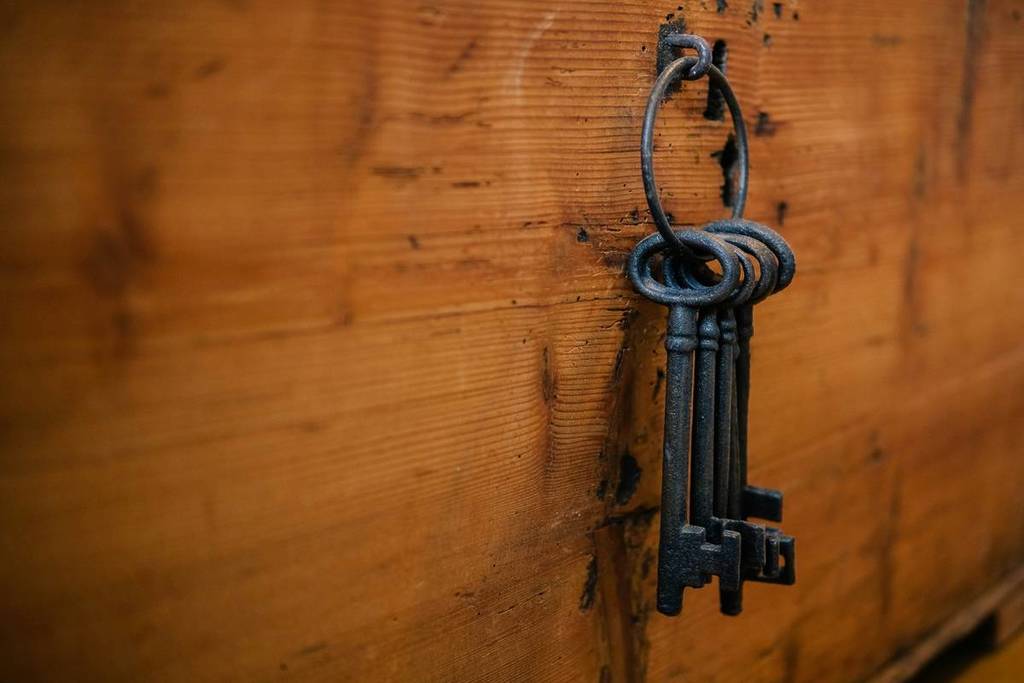 Several keys hang on a wooden peg.