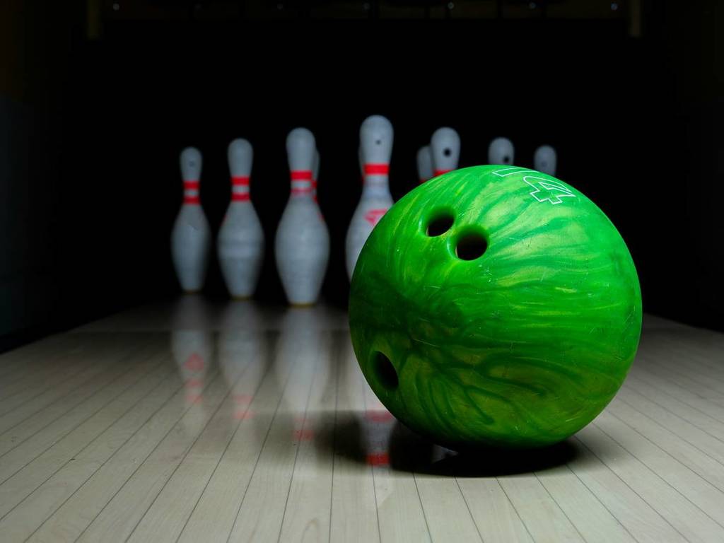 A green bowling ball and pins at a bowling alley.