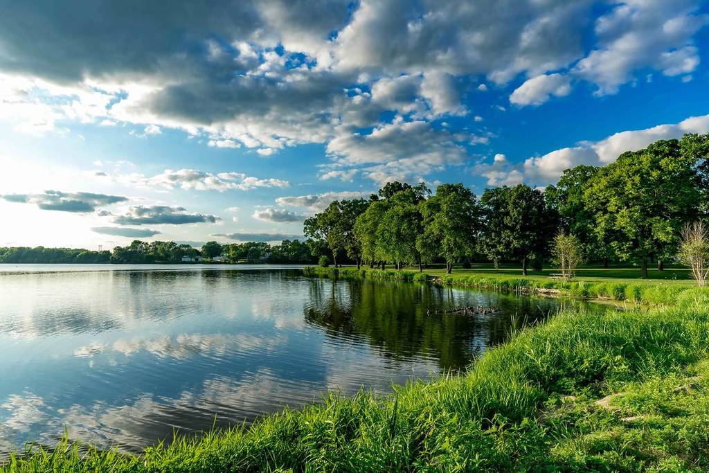 Un pequeño lago junto a un bosque verde en la zona rural del sur de Wisconsin, EE.UU., fotografiado ocho antes de la puesta de sol.