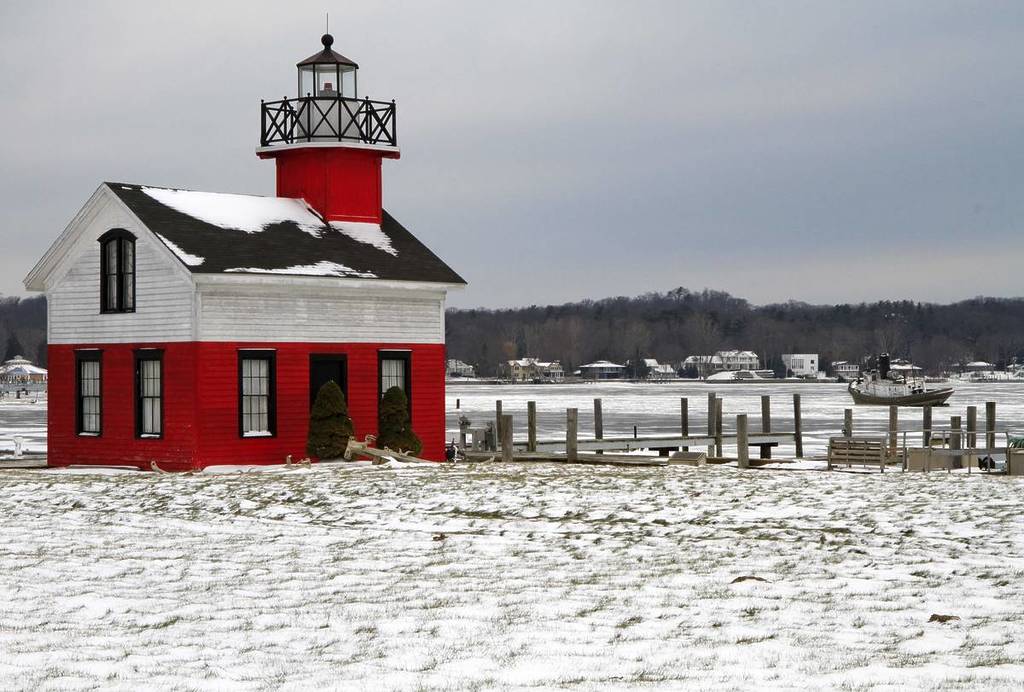 There is little activity at the Kalamazoo River Lighthouse. An old tug boat sits stranded in the icy river during the early part of winter. Saugatuck, Michigan, USA.