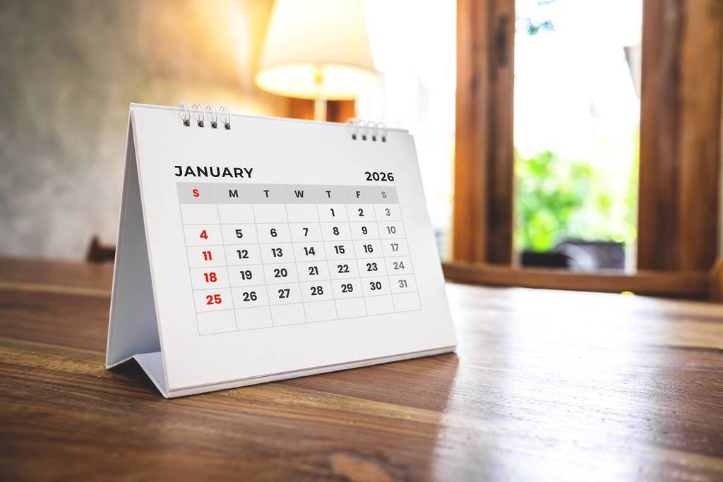 Blanco enero 2026 calendario de escritorio sobre mesa de madera sobre fondo borroso cafetería. Concepto de feliz año nuevo