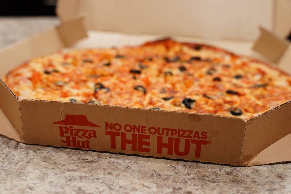 Cooked Pizza Hut thin crust pizza in a delivery box.