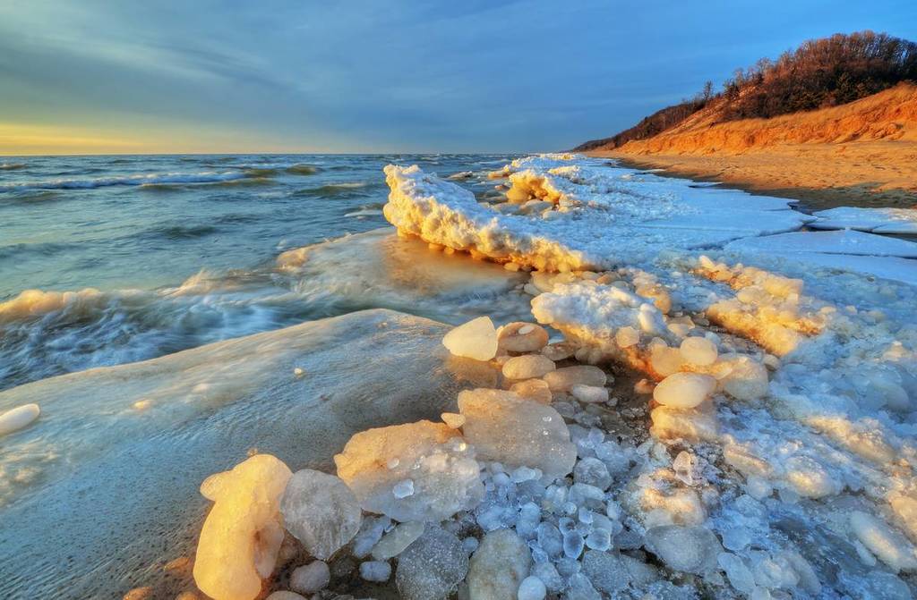 Landscape of iced winter shoreline of Lake Michigan with splashing wave, Saugatuck Dunes State Park, Michigan, USA