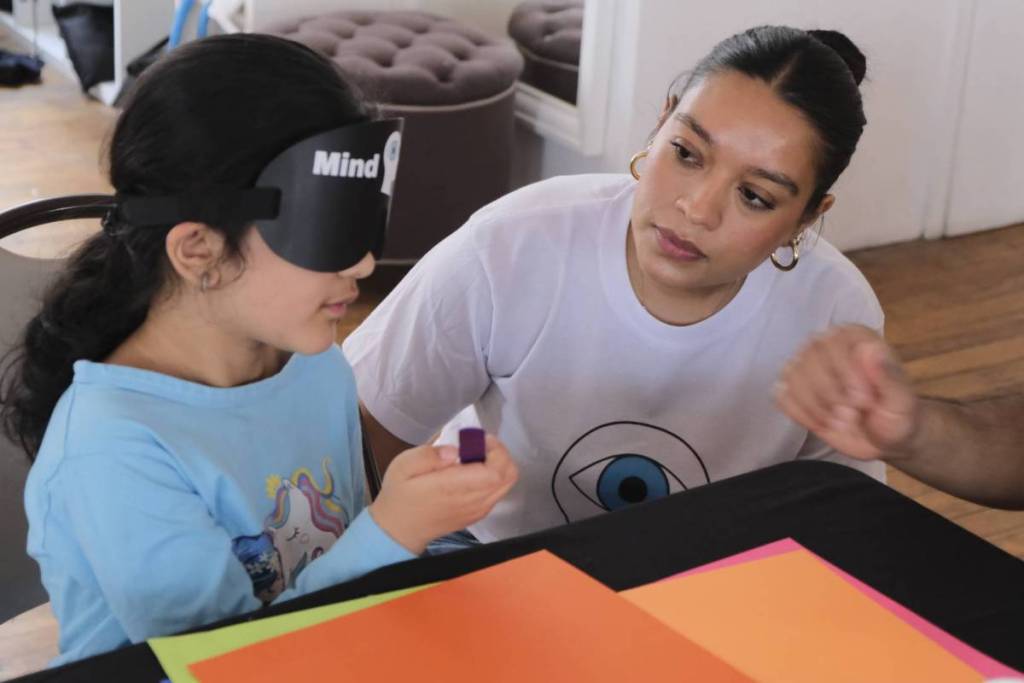 A girl holding a pen as a woman guides her through an exercise at Superminds Academy