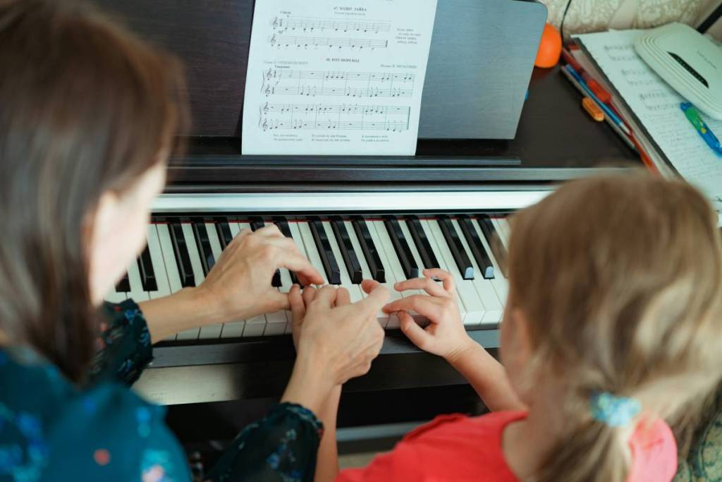 Una madre y su hijo tocan el piano juntos.