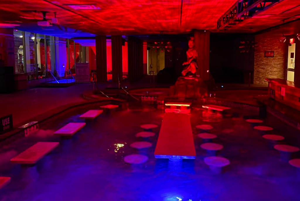 Image shows a pool immersed in ambient lighting at Spa Castle Texas.