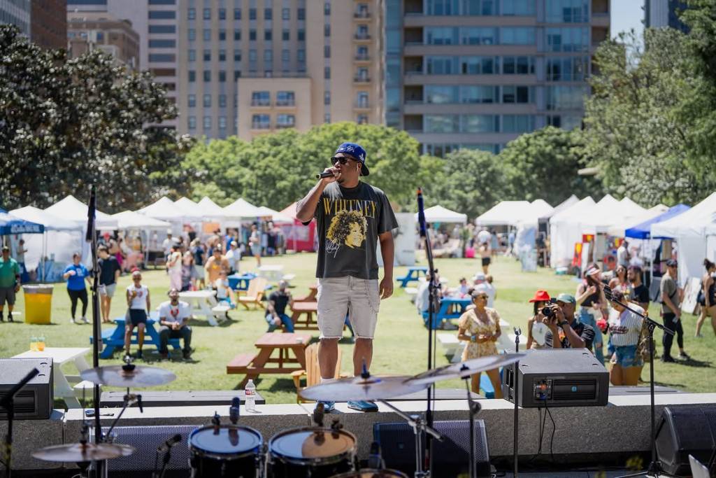 La imagen muestra a un artista actuando en el Festival de Arte y Música del centro de Dallas. 