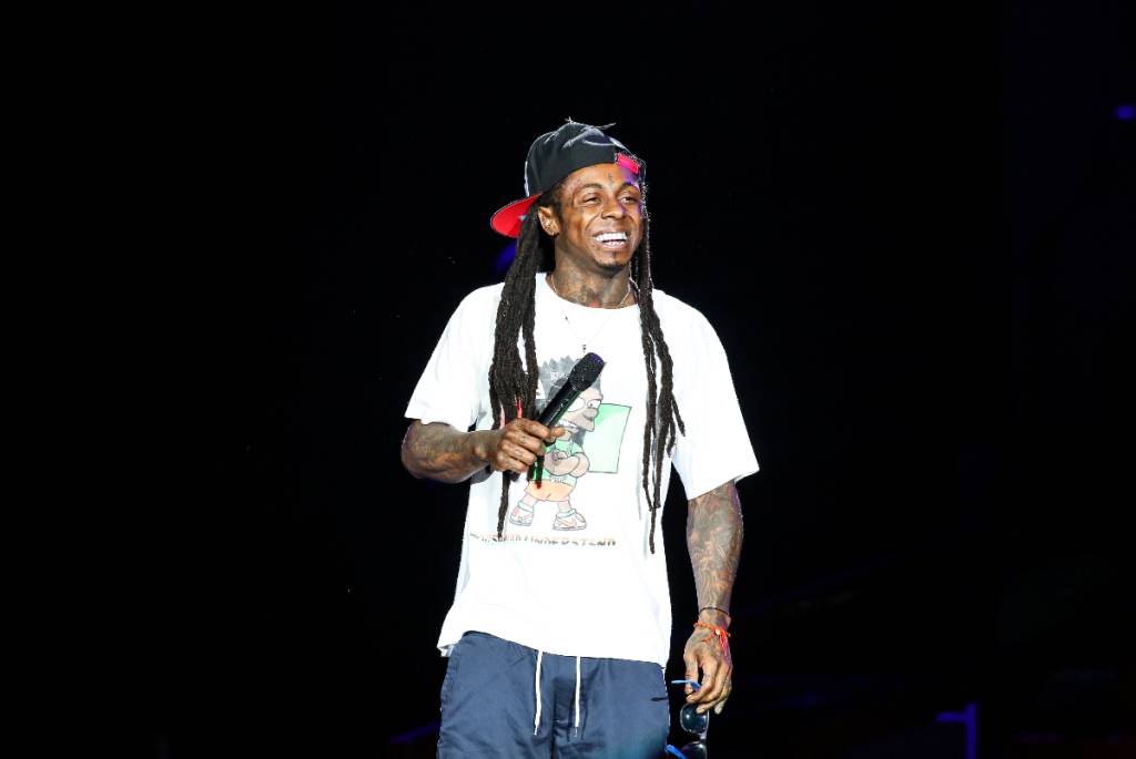 La imagen muestra a Lil Wayne en el escenario durante un concierto.