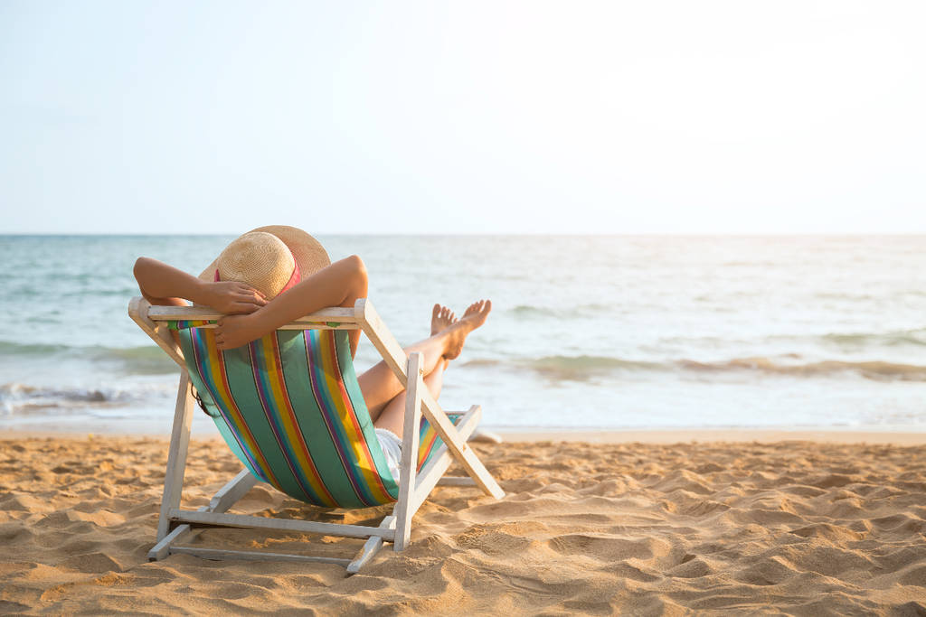 Image shows a person relaxing on a beach.