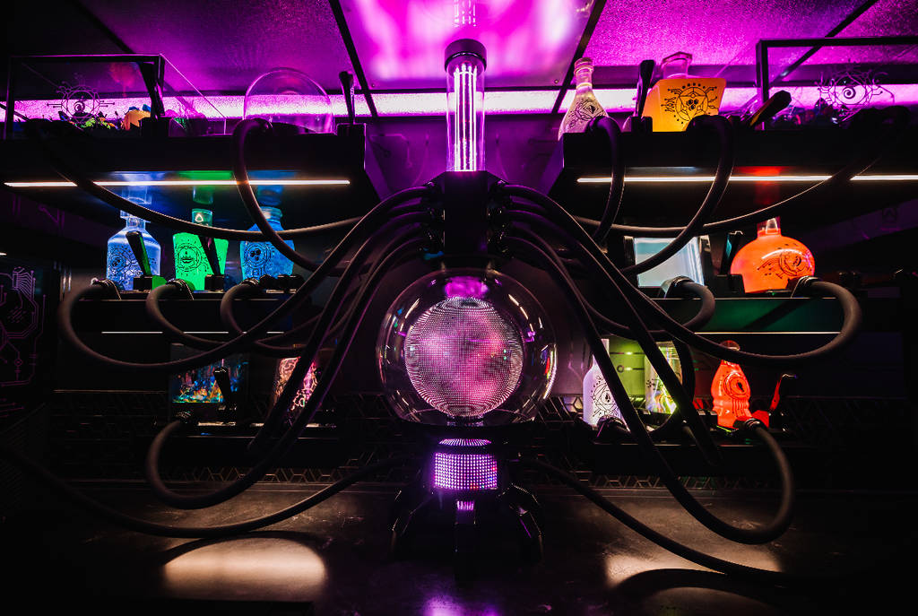 Image shows a series of glowing tubes and elixers inside Meow Wolf Grapevine's Prime Materia bar.