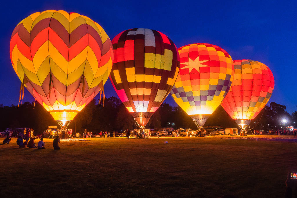 Image shows hot air balloons lit up at night.