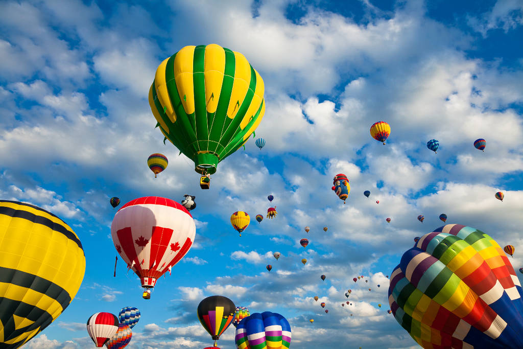 Image shows hot air balloons taking off from the ground into the sky
