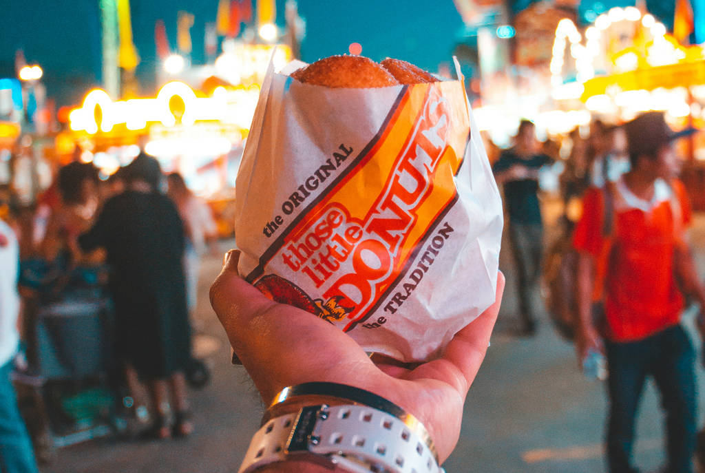 Image shows someone holding up a donut at a carnival.