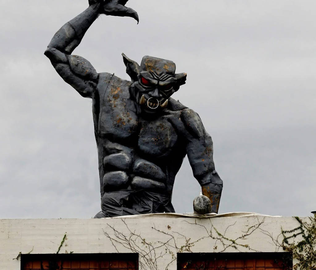 Image shows a gargoyle-like demon figure atop of Cutting Edge Haunted House in Fort Worth.