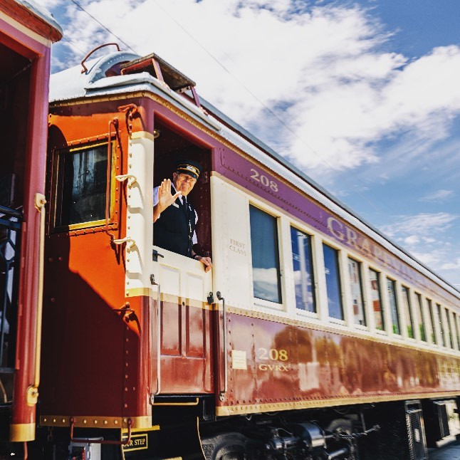 Image shows a conductor posing from the window of a train.