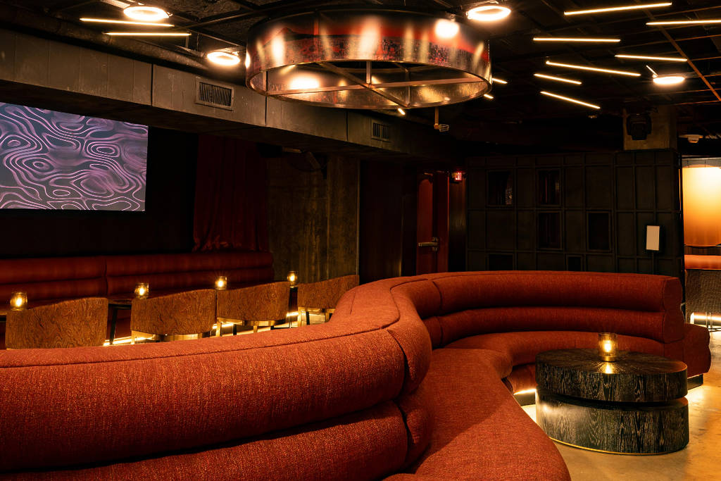 Image shows the serpentine booth and gold chandelier inside AKAI speakeasy in Dallas