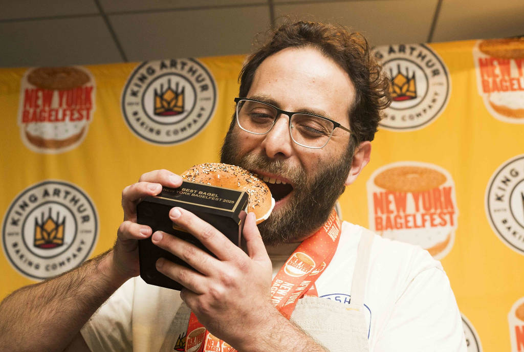 Image shows Starship Bagel founder, Oren Salomon pretending to bite bagel-shaped trophy at BagelFest 2025.