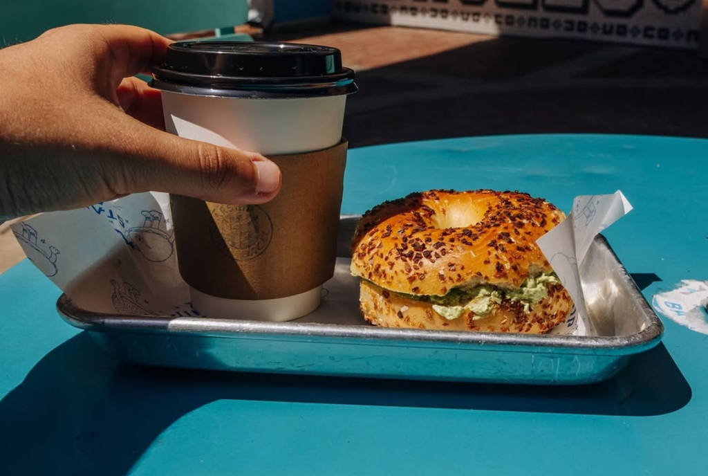 Image shows a bagel and coffee on a tray on a counter at Starship Bagel in Dallas, Texas.