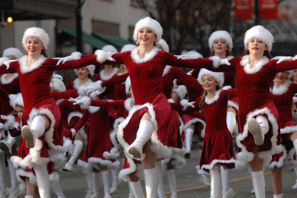Imagen de un grupo de bailarinas disfrazadas de Papá Noel en un desfile navideño.