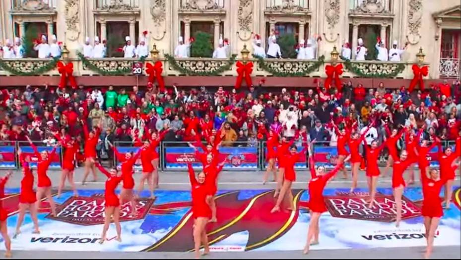 Image shows a group of costumed dancers performing at the Dallas Holiday Parade.