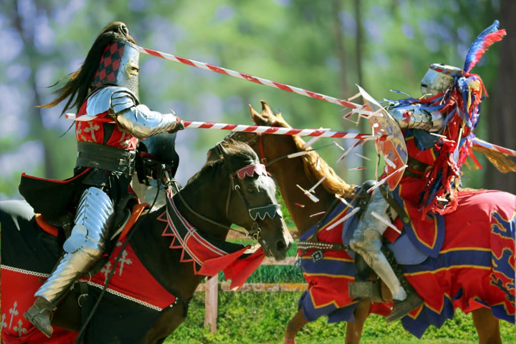 Image shows two people in traditional knight costumes jousting on horses.