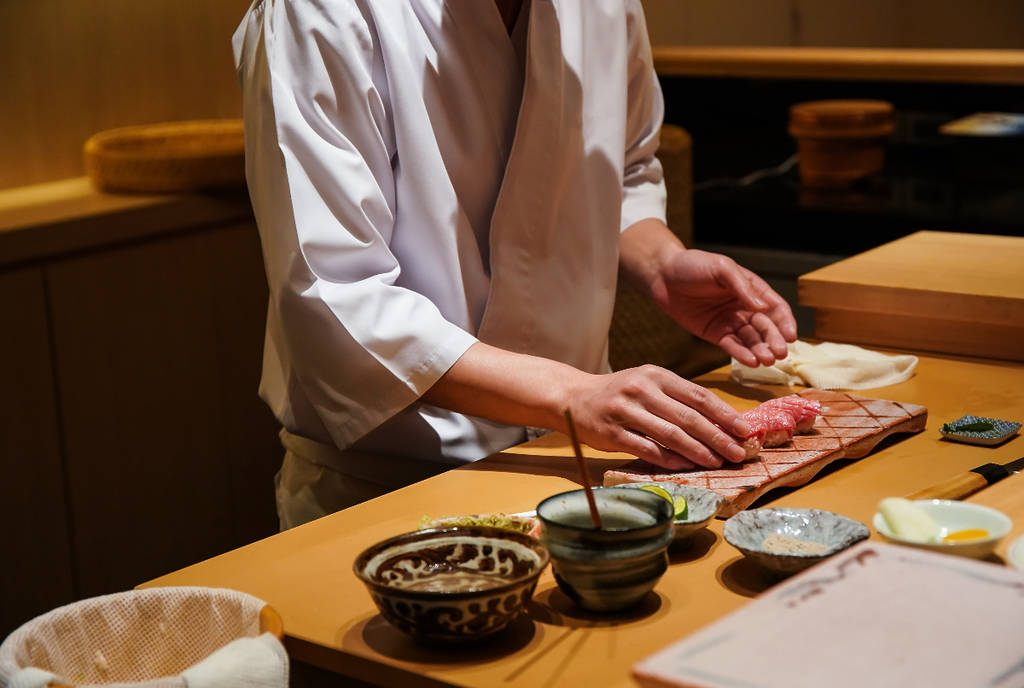 Image shows a chef preparing sushi.