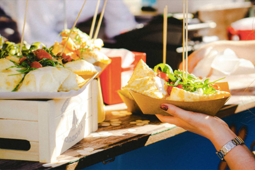 Image shows someone ordering a plate of food at a food festival.
